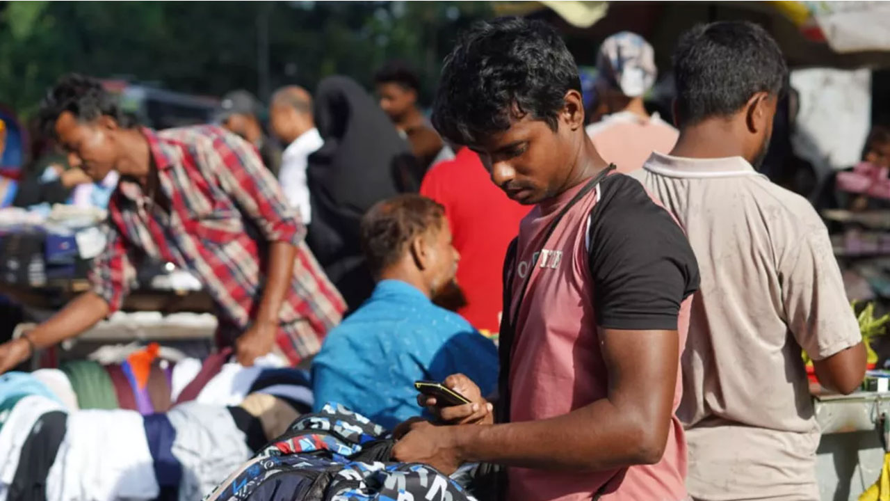 রাজধানীর গুলিস্তান এলাকায় বাটন ফোন ব্যবহার করছেন এক তরুণ। ছবি: ইউএনবি