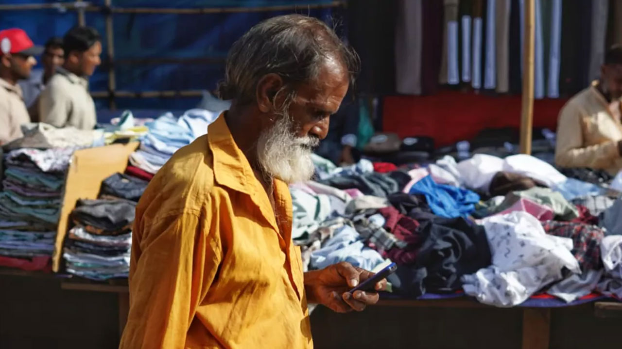 রাজধানীর একটি বাজারে মোবাইল ফোন হাতে এক ব্যক্তি। ছবি: ইউএনবি